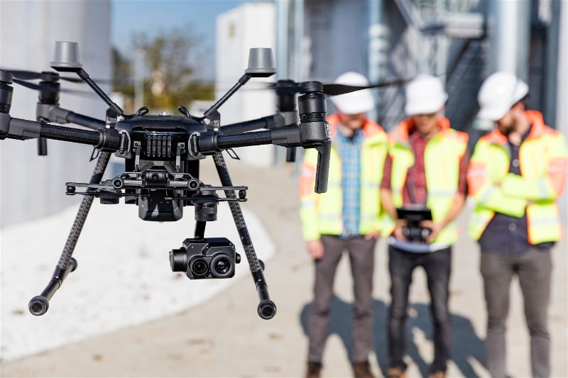 Imagem de três profissionais do ramo da indústria manuseando um drone em um trabalho 